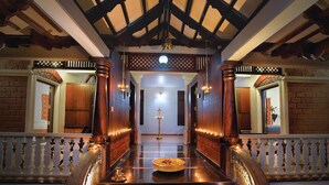 A grand hallway with a central table featuring a decorative bowl, flanked by ornate columns and a white balustrade. - Wetzlar Resorts and Hotels (Muvattupuzha)