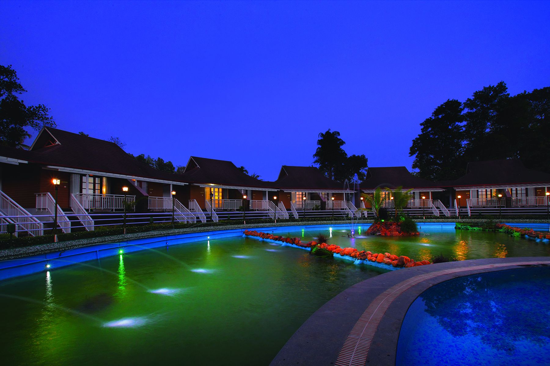 Ein Hotel mit mehreren Gästezimmern, einem Schwimmbad und einer Springbrunnen.