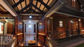 A traditional wooden house with a porch, a dining area with a table and chairs, and a small garden. - Wetzlar Resorts and Hotels (Muvattupuzha)