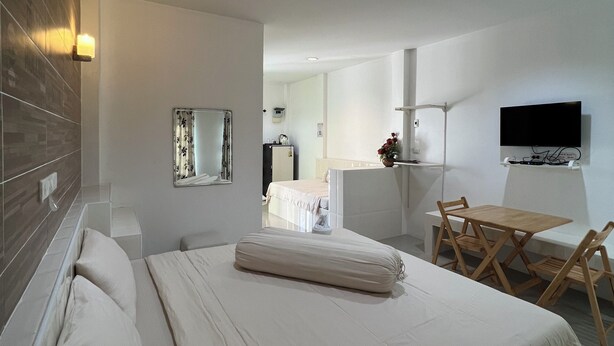 A modern hotel room with a neatly made bed, a desk with a chair, a flat-screen TV mounted on the wall, and a large mirror. - Saraburi Garden Resort (Saraburi)