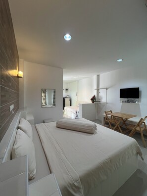 A modern hotel room with a neatly made bed, a desk with a chair, a flat-screen TV mounted on the wall, and a large mirror. - Saraburi Garden Resort (Saraburi)