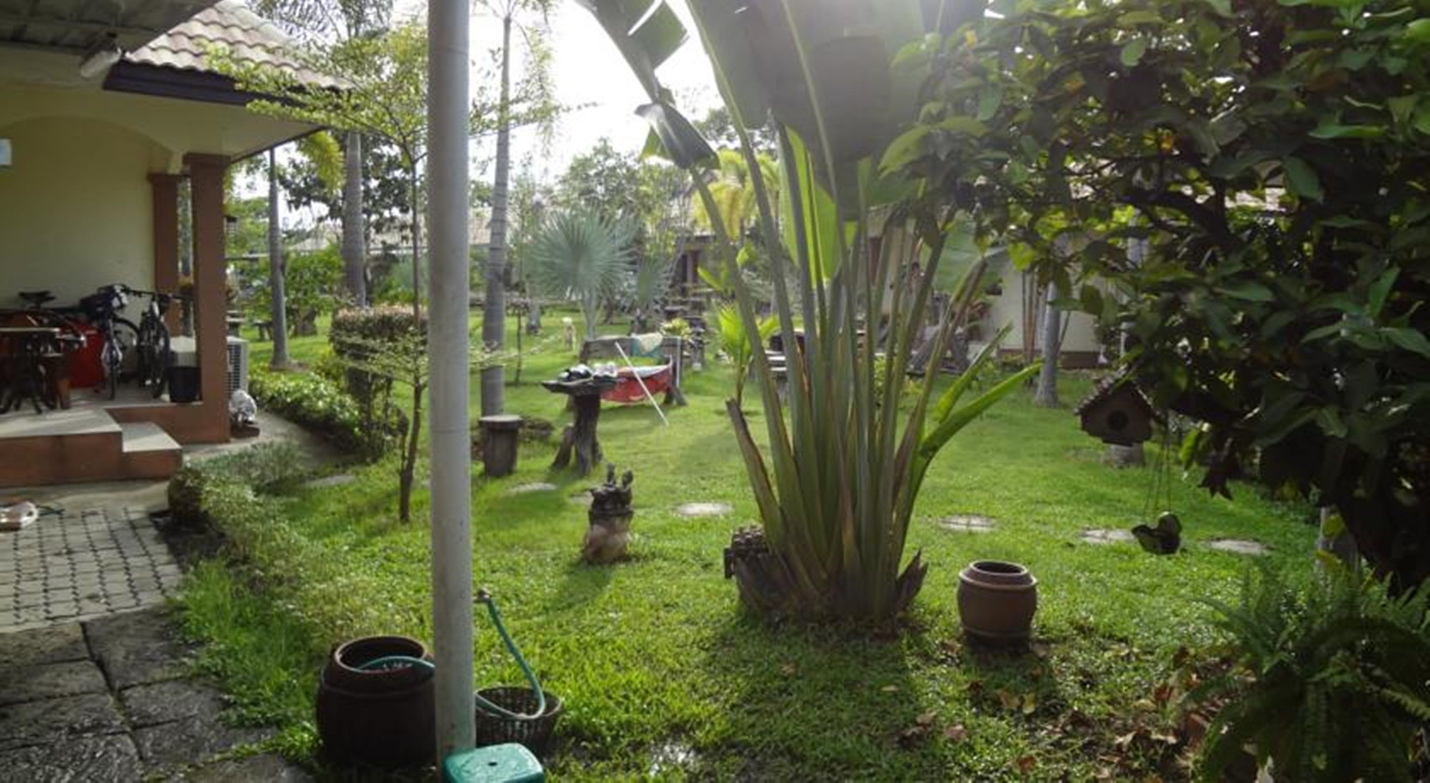 Un jardín con patio, bicicletas y mobiliario exterior.