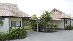 A two-story building with a tiled roof, a covered patio area, and a small garden with tropical plants. - Saraburi Garden Resort (Saraburi)