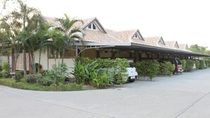 A row of single-story buildings with a covered patio area, surrounded by tropical vegetation. - Saraburi Garden Resort (Saraburi)