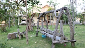 A rustic wooden structure in a garden with a house in the background. - Saraburi Garden Resort (Saraburi)