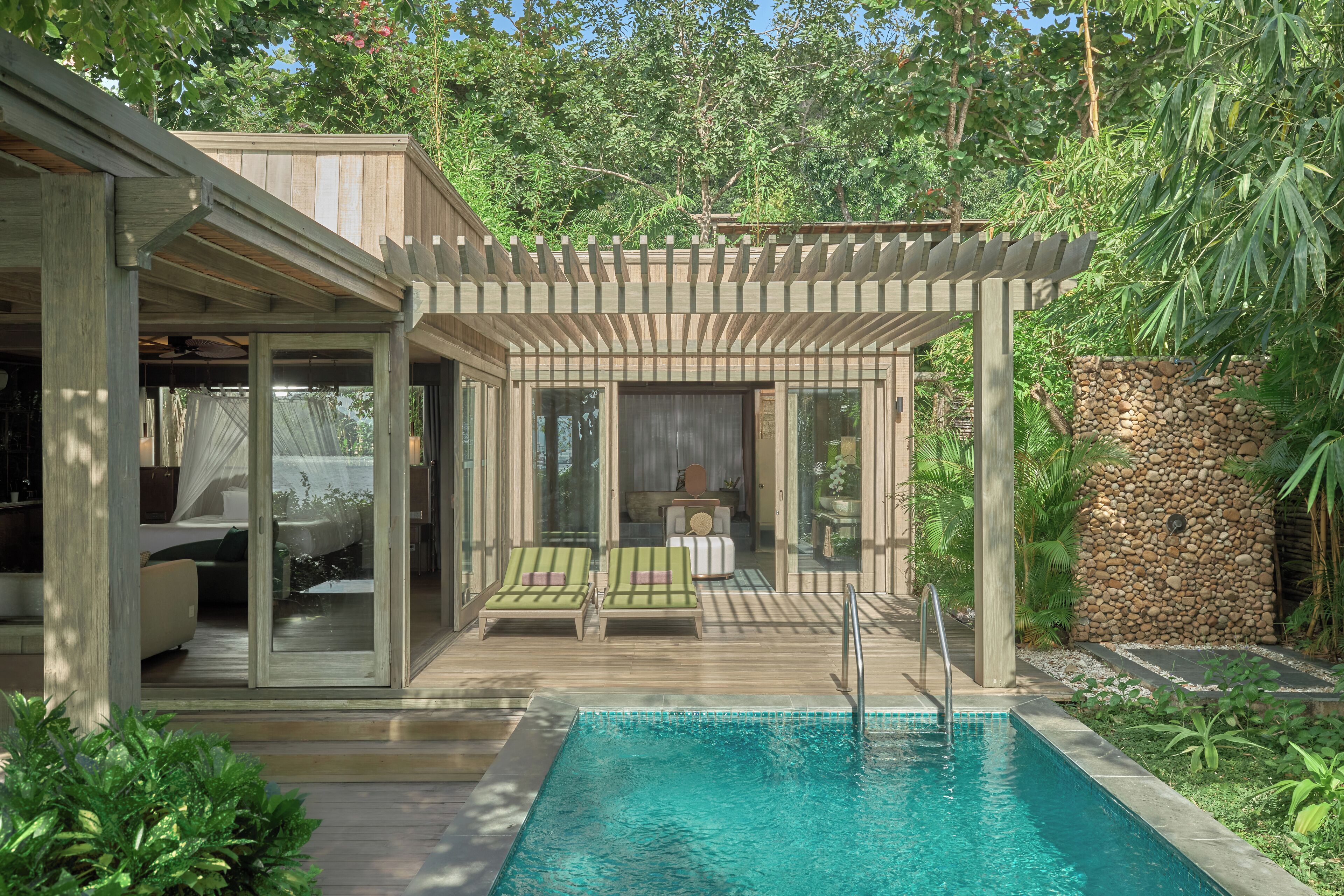 A modern outdoor pool area with a wooden deck, lounge chairs, and a pergola.