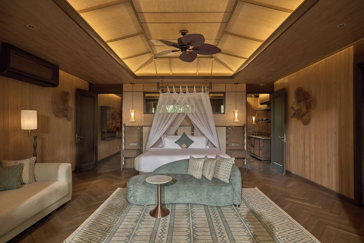 Ein geräumiges Schlafzimmer mit Baldachinbett, einer Sitzecke mit rundem Tisch und einem Deckenventilator.