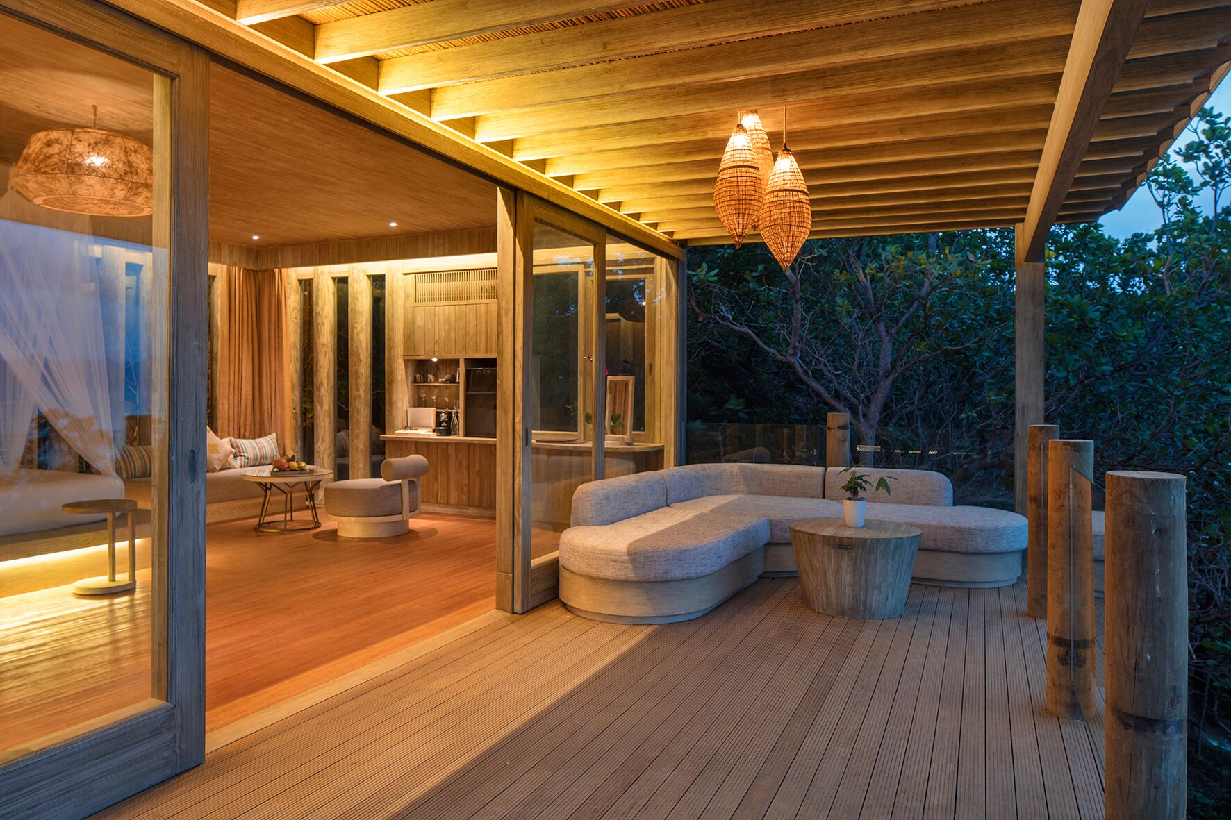 A modern outdoor living area with a wooden deck, built-in seating, and a glass enclosure.