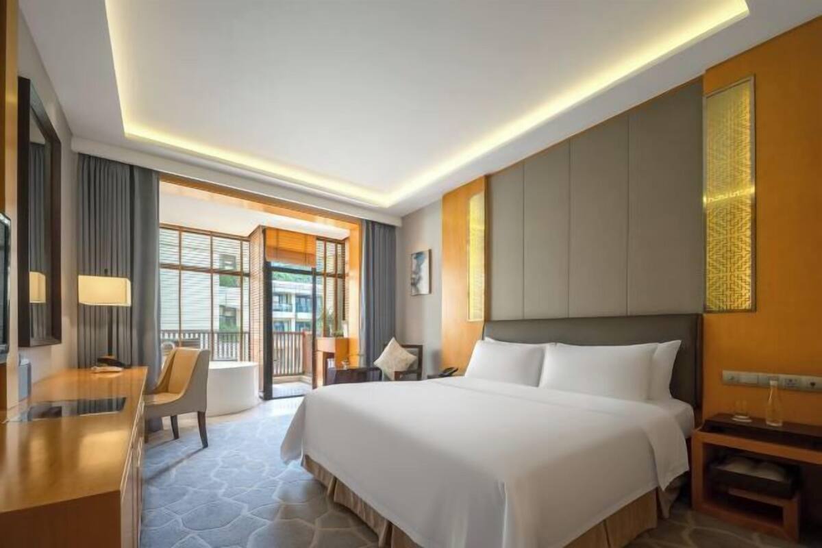 Een hotelkamer met een bed, bureau, stoel en een balkon.