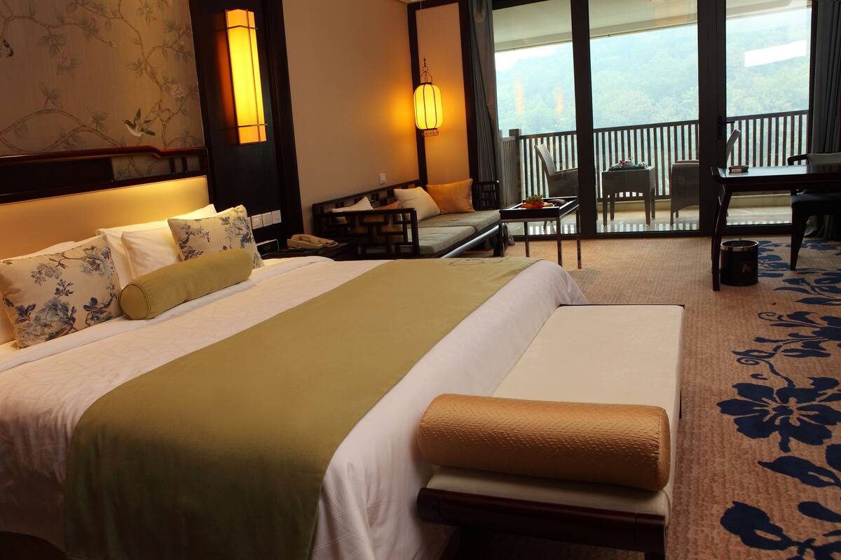 Een hotelkamer met een groot bed, een bureau en een balkon met uitzicht.