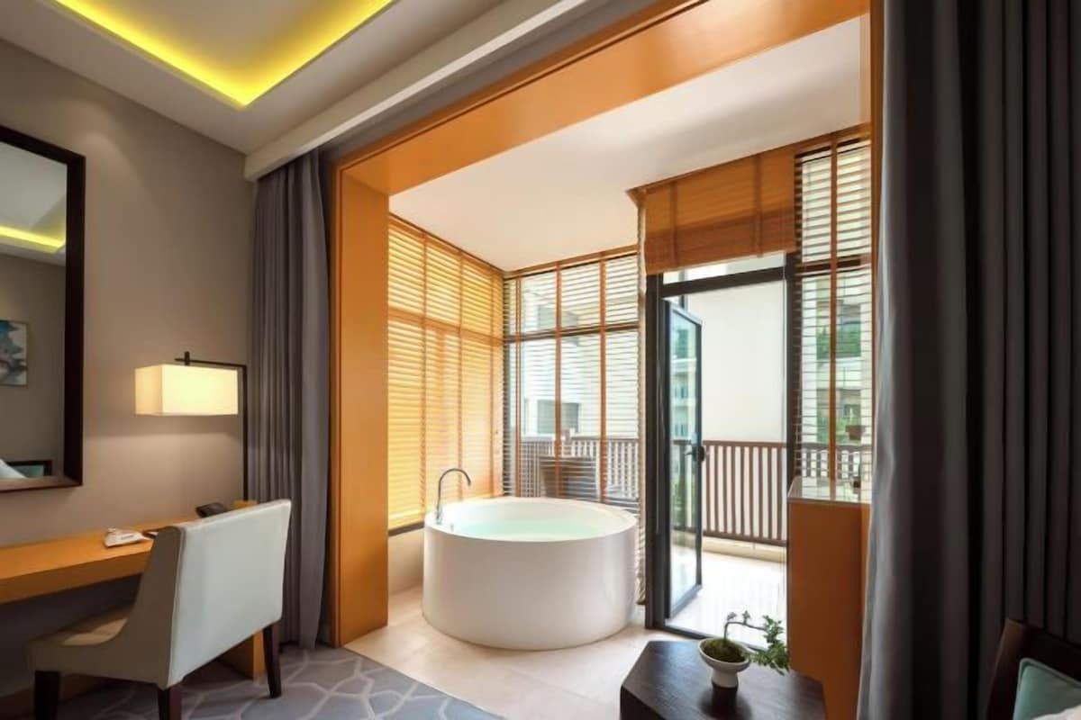 Un baño moderno con bañera, tocador con espejo y ventana con persianas.