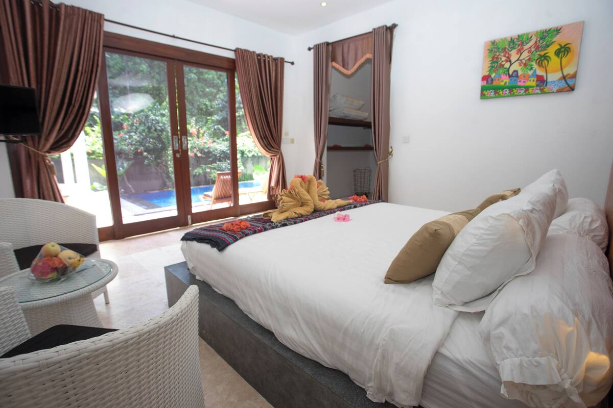 Un dormitorio con una cama, una mesita con fruta y vistas al exterior.