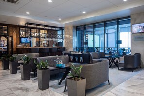 Een moderne lobby met zithoeken, een bar en grote ramen.