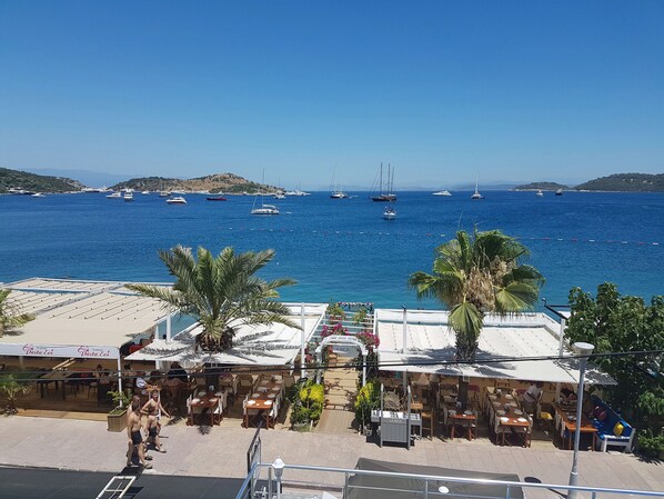 A coastal restaurant with outdoor seating overlooking a marina with sailboats. - Knidos Hotel (Bodrum)