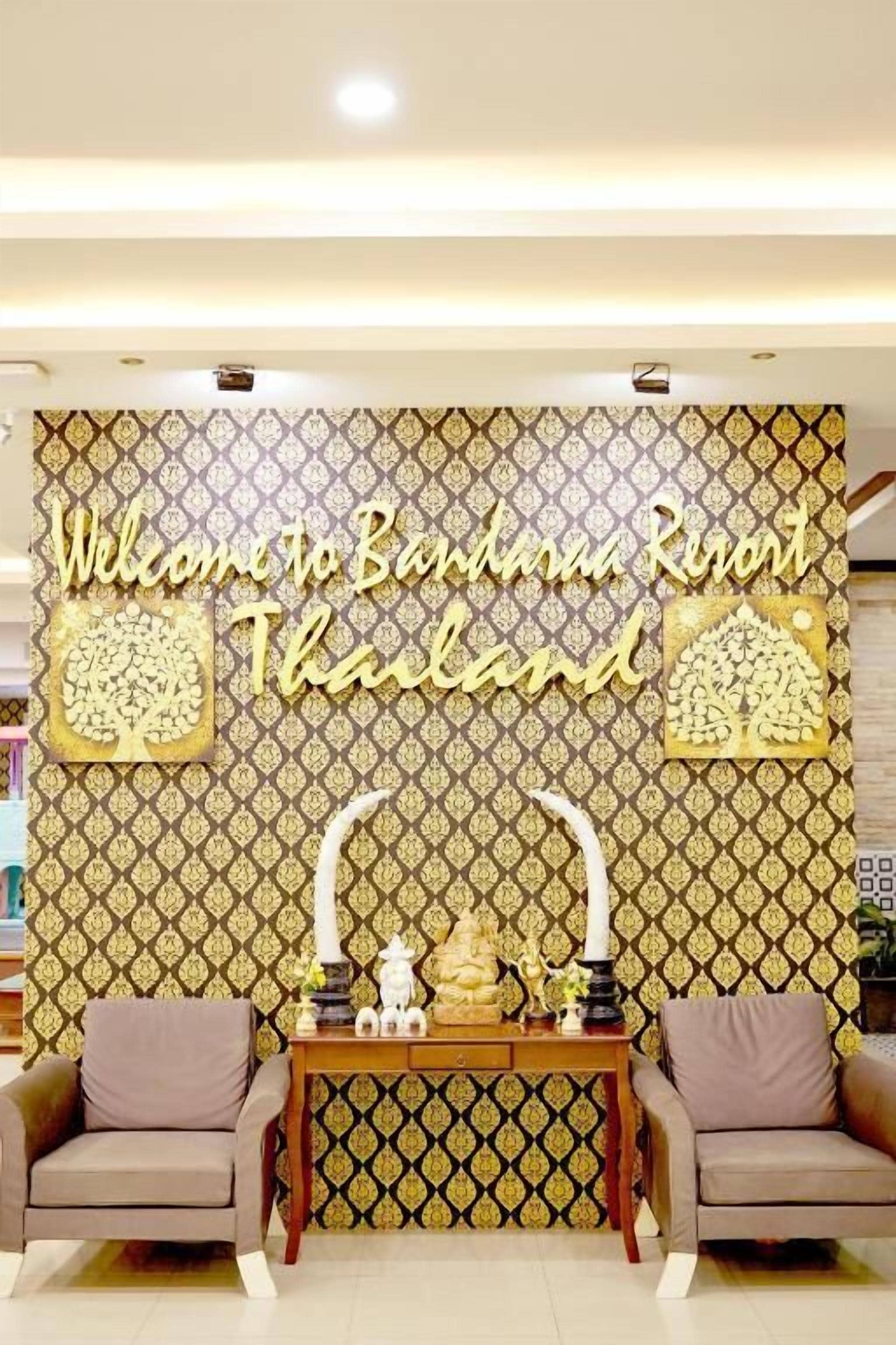 A reception area with a patterned wall, a welcome sign, and a reception desk with two chairs.