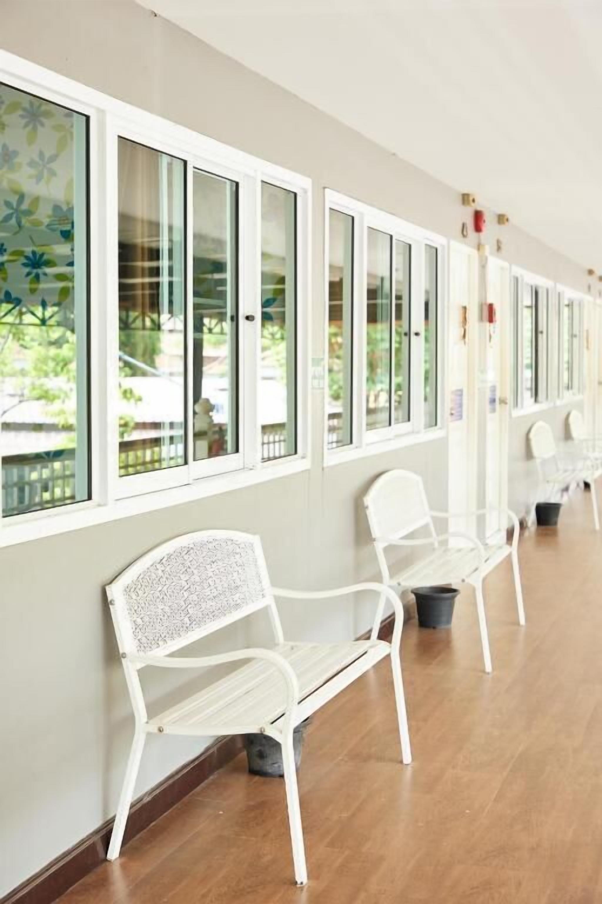 A corridor with white benches and a row of windows.