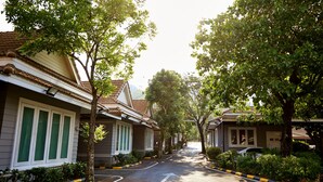 A row of single-story houses with a paved driveway and a clear path marked by a yellow and black curb. - Baandara Resort Saraburi (Saraburi)