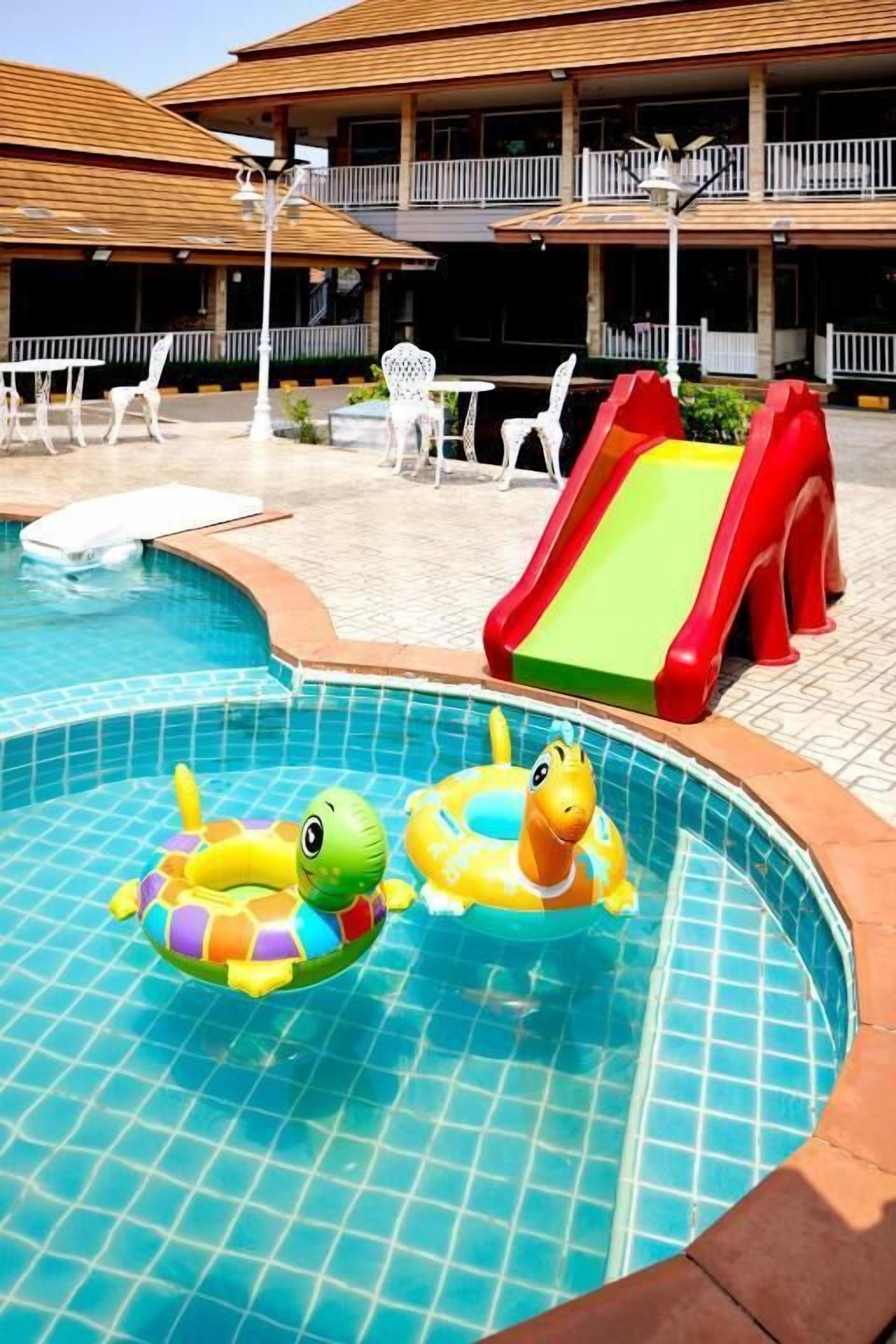 A swimming pool with two inflatable toys, a slide, and outdoor seating.