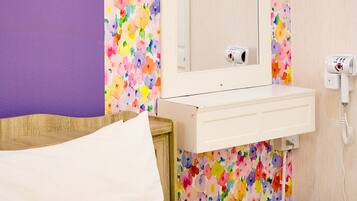 Una habitación de hotel con una cama, una mesita de noche, un espejo y una pared con diseño floral.