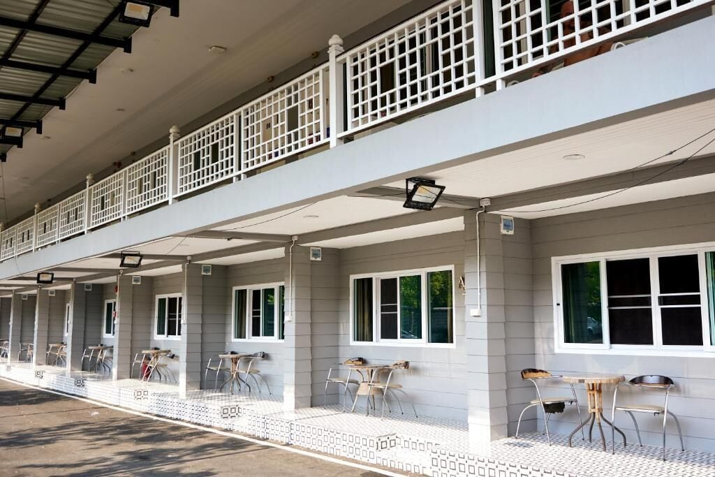 A row of rooms with individual windows and a covered outdoor area with tables and chairs.