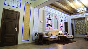 A traditional interior with ornate wall decorations, a chandelier, and a sofa set. - Grand Emir Residence (Bukhara)