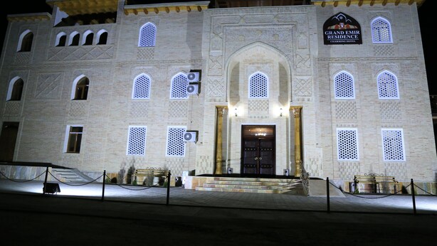 A building with a grand entrance, multiple arched windows, and a sign indicating it is the Grand Emir Residence. - Grand Emir Residence (Bukhara)