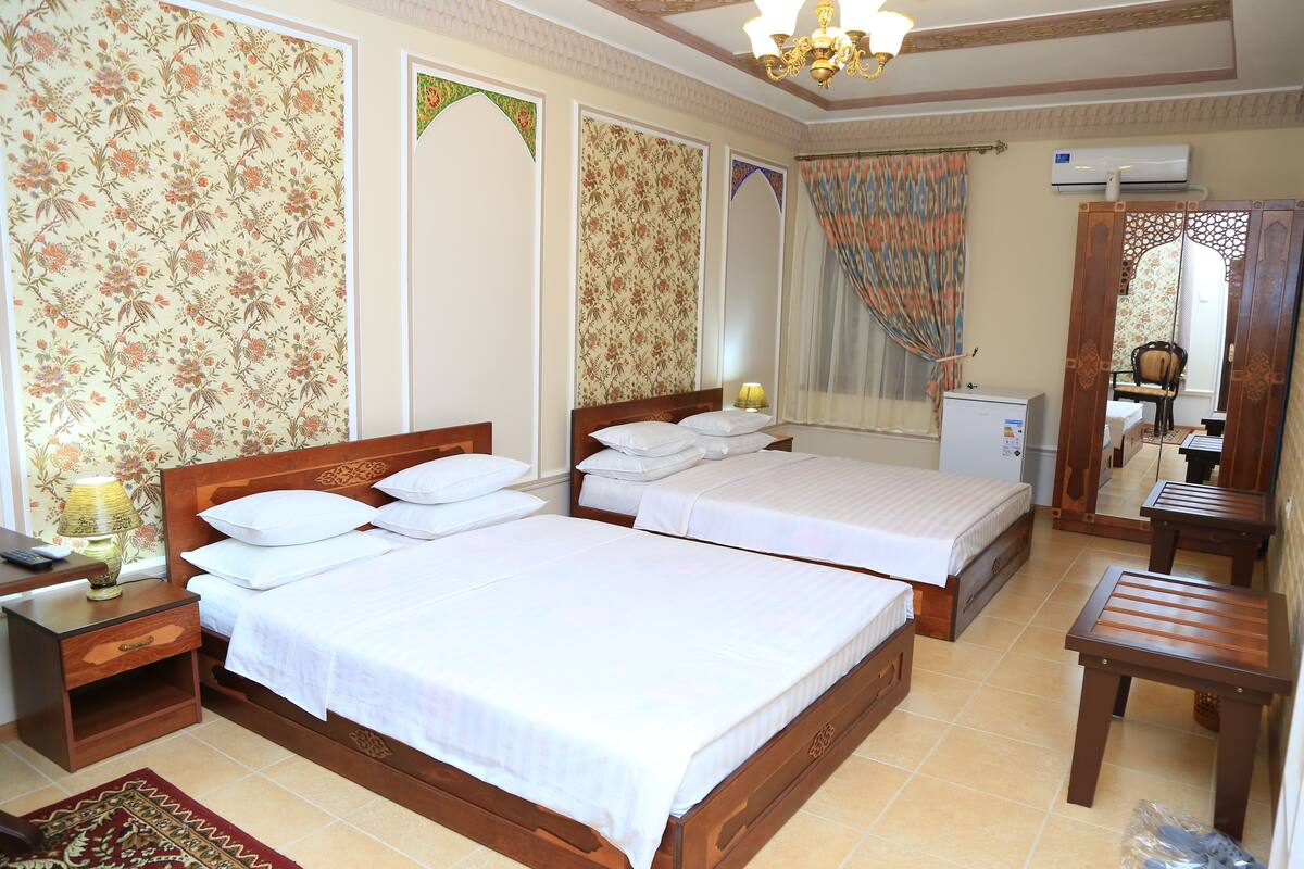 A hotel room with two beds, a desk, a chair, and an air conditioning unit.