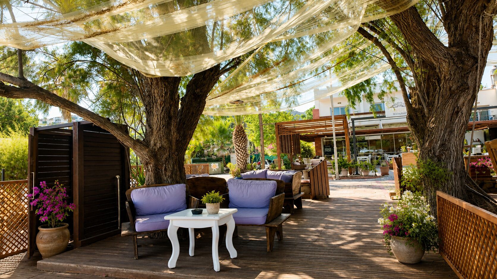 An outdoor patio with wooden furniture, a white table, and potted plants.