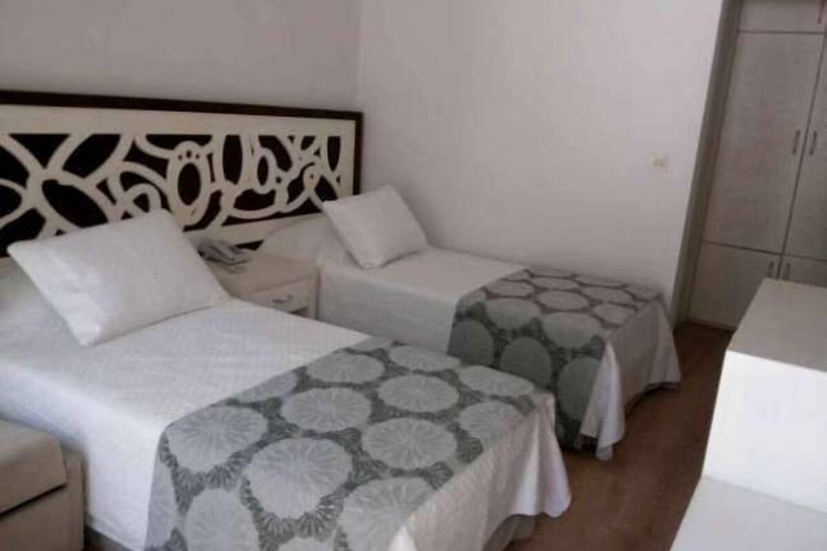 A simple, clean room with two single beds, a nightstand, and a wardrobe.