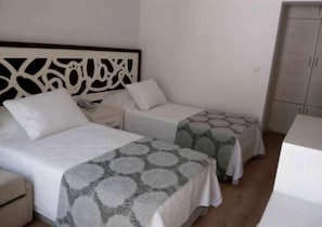 A simple, clean room with two single beds, a nightstand, and a wardrobe.