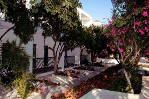 A courtyard with white buildings, trees, and flowering plants. - Meggs Bodrum Beach Hotel (Bodrum)