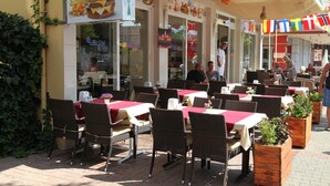 An outdoor cafe with tables and chairs, a menu board, and a Coca-Cola sign. - Alin Hotel (Alanya)