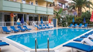 A pool area with blue lounge chairs, a lifebuoy, and umbrellas. - Alin Hotel (Alanya)