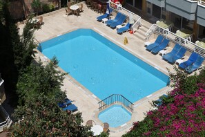 Una piscina al aire libre, sombrillas, sillones reclinables de piscina