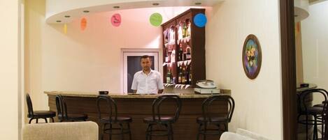 Una zona de bar con mostrador, taburetes y un espacio de estar con sofás.