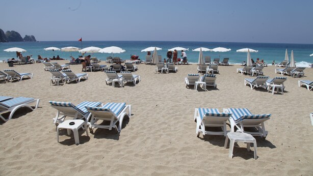 A beach with rows of sun loungers and umbrellas, some occupied by people. - Alin Hotel (Alanya)