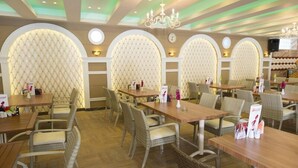 A restaurant with multiple tables and chairs, arched wall designs, and a chandelier. - Lavinia Apart Hotel (Alanya)