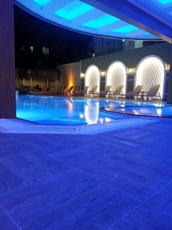 A swimming pool with lounge chairs and arched wall designs.