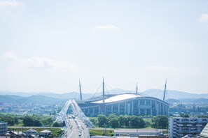 Un stade doté d’un grand toit et de nombreux câbles de soutien, entouré d’un pont et de verdure.