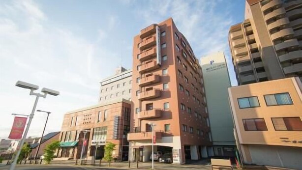 A multi-story building with a central courtyard, surrounded by other buildings. - Toyota Prestige Hotel (Toyota)