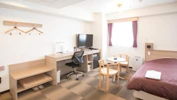Habitación de hotel con cama, escritorio, silla y una pequeña mesa.