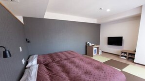 A modern hotel room with a large bed, a flat-screen TV mounted on the wall, and a small desk with a chair. - Toyota Prestige Hotel (Toyota)