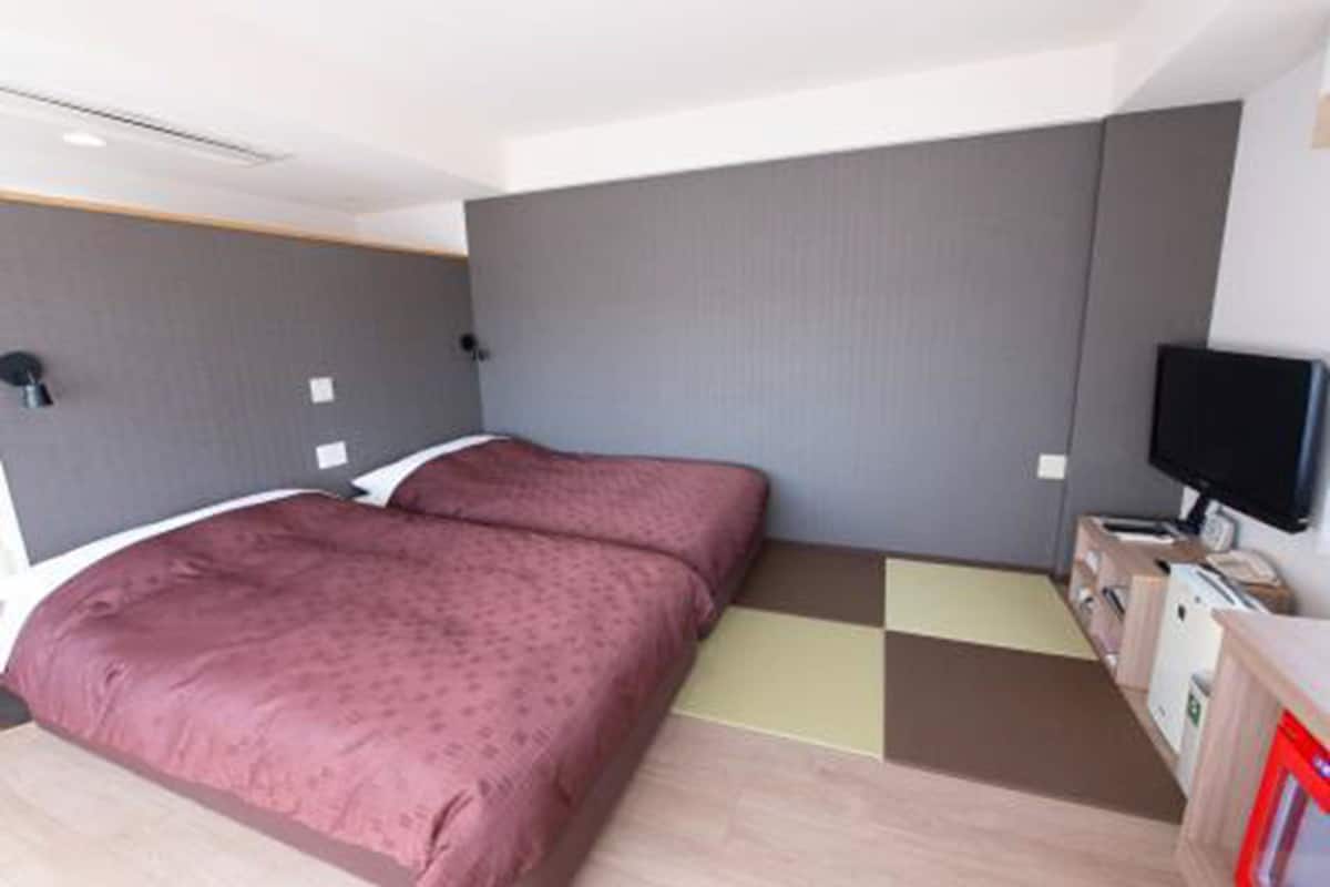 Una camera da letto con un letto, una televisione e una scrivania con un computer.