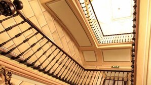 Una imponente escalera con barandillas ornamentadas y un techo alto.