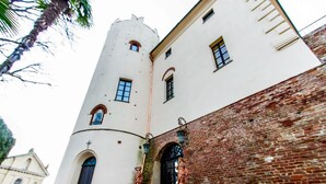 Un edificio histórico con fachada blanca, base de ladrillo y una torre con ventanas de arco.