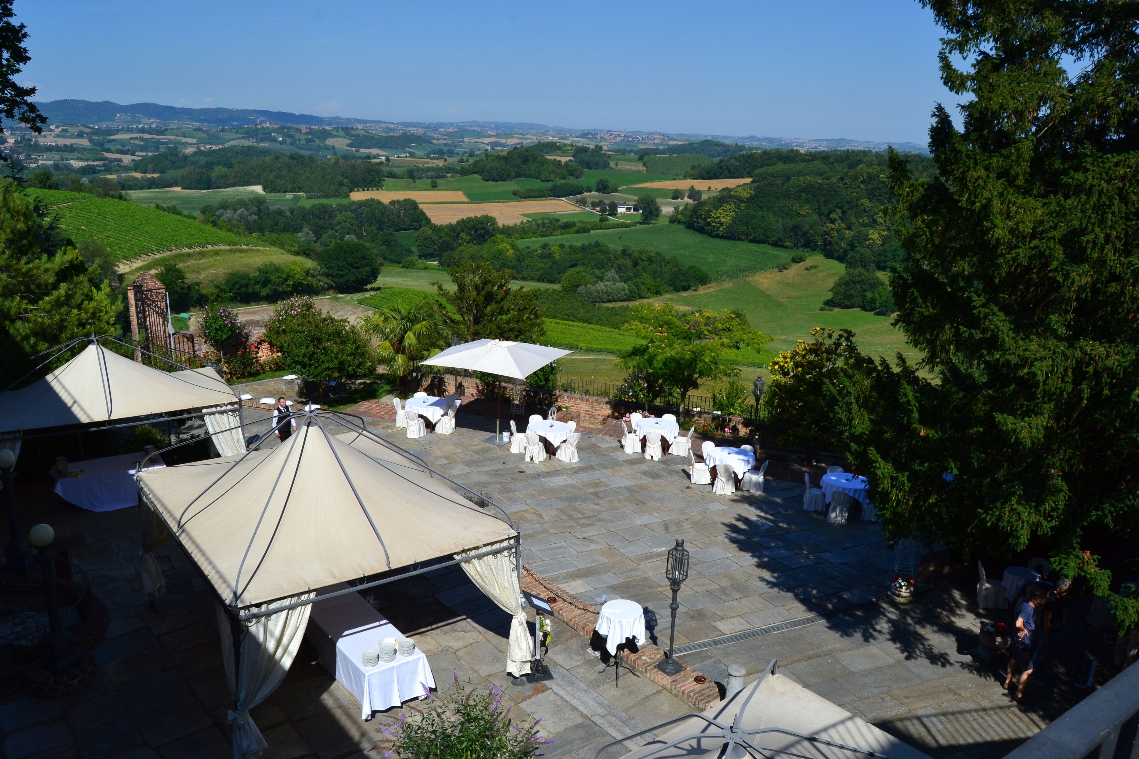 Un espacio para eventos al aire libre con carpas y mesas dispuestas, con vistas a un paisaje pintoresco con campos y árboles.