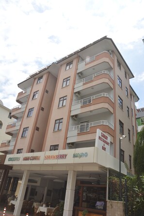 A multi-story building with a restaurant and bar on the ground floor, featuring signs for cocktails, Irish coffee, strawberry, and mojito. - Saray Apart Hotel (Alanya)