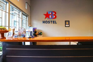 A reception desk with a sign reading "B HOSTEL" and a framed certificate on the wall. - DD Living - Hostel (Tibubeneng)