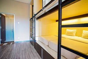 A bunk bed room with a wooden floor, a door, and a wall-mounted air conditioning unit. - DD Living - Hostel (Tibubeneng)