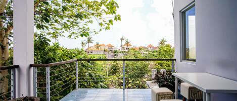 A balcony with a view of houses and greenery.